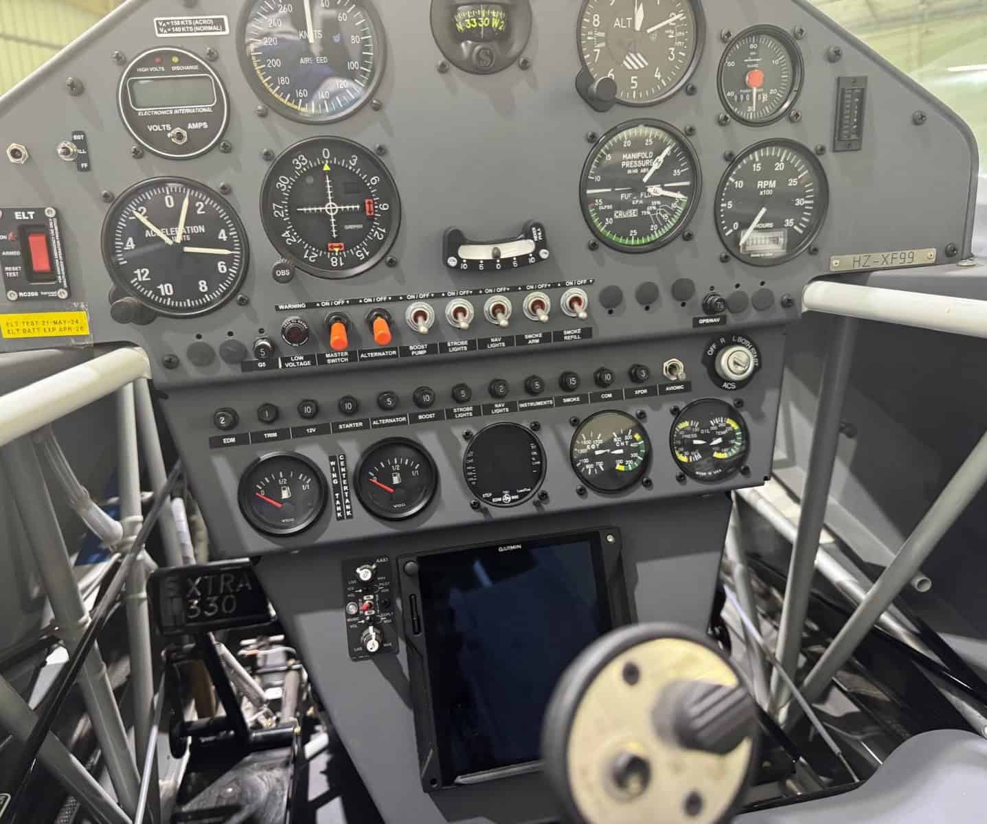 Close-up of Extra 330LX HZ-XF99 cockpit panel with analog flight instruments and switches