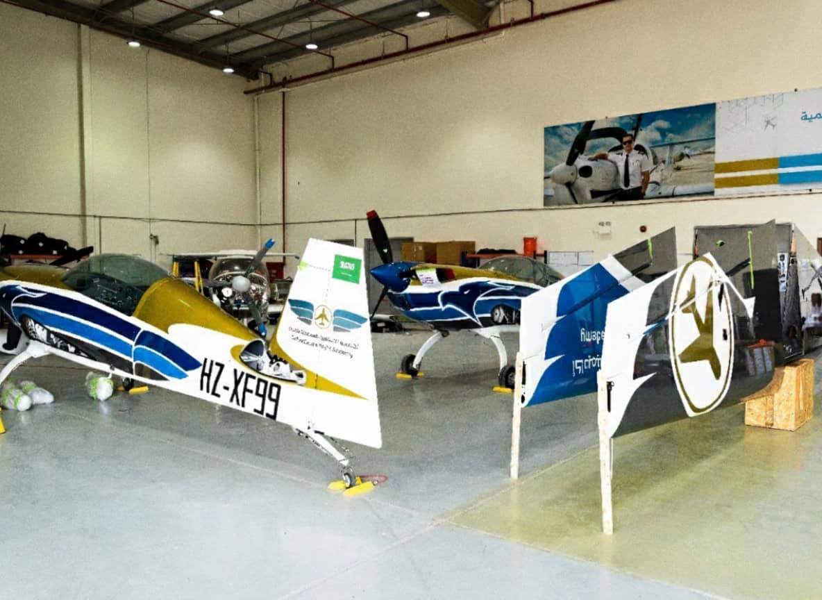 Extra 330LX HZ-XF99 inside hangar next to another aircraft and detached cowling